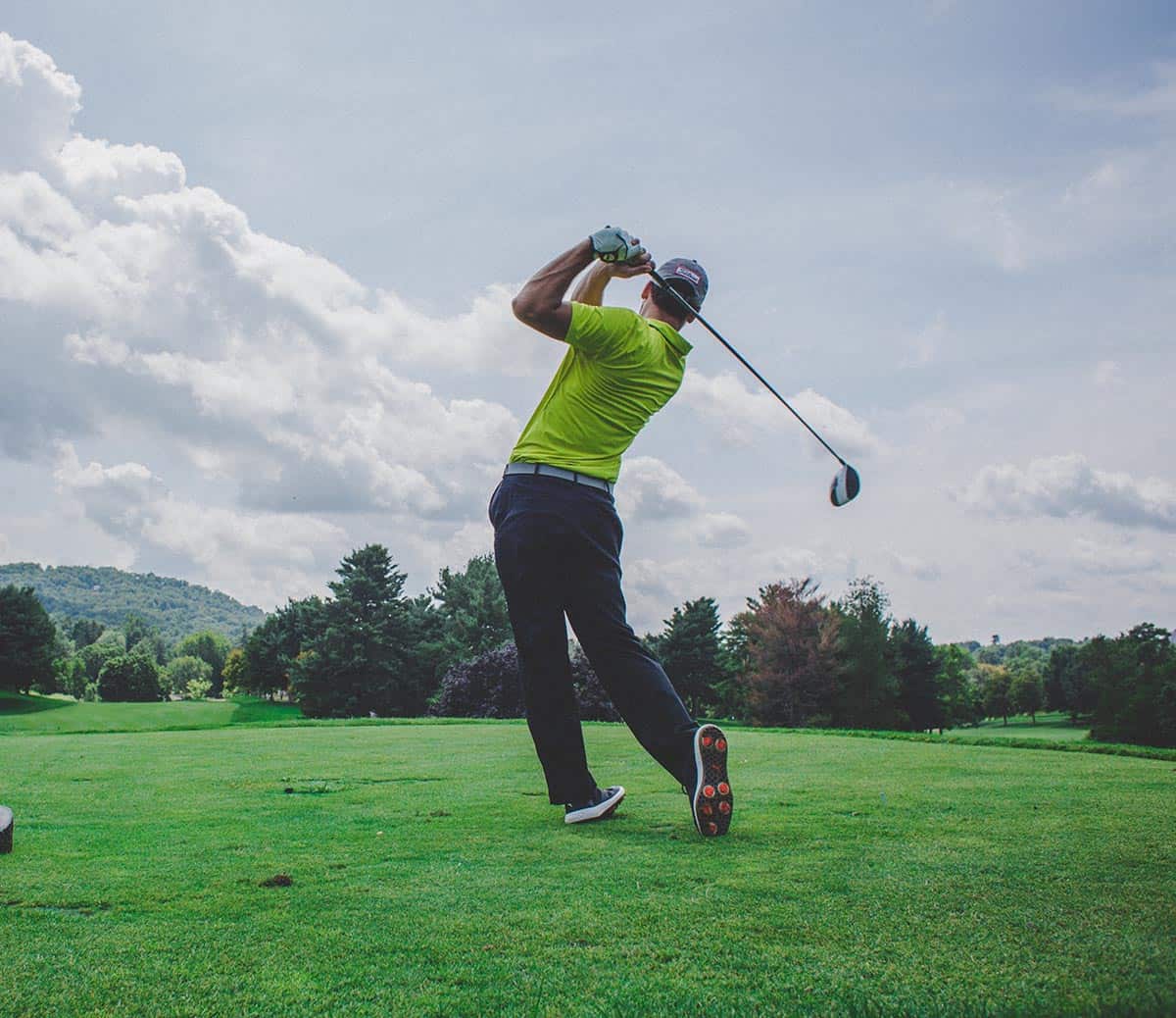 man playing golf in sunny day in green countryside